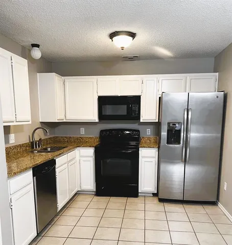 a kitchen with granite countertop a refrigerator and a sink