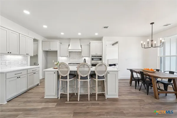 a kitchen with cabinets a sink dining table and chairs