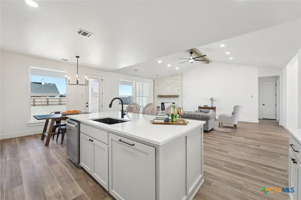 a kitchen with sink and white cabinets with wooden floor