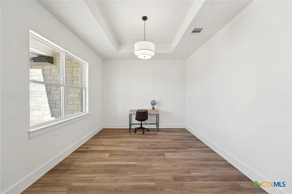 a living room with wooden floor windows and a ceiling fan