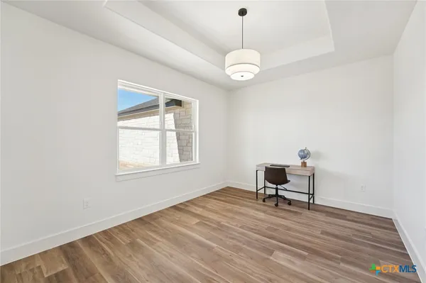 a view of a workspace with wooden floor and a window