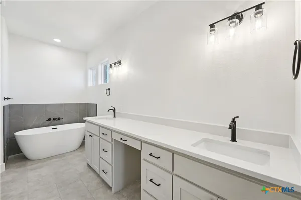 a spacious bathroom with a double vanity sink mirror and bathtub