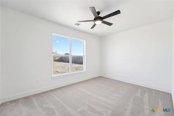 an empty room with a ceiling fan and windows