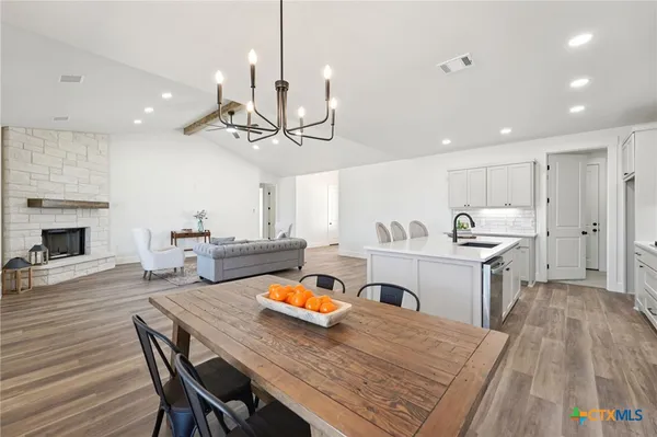 a kitchen with stainless steel appliances granite countertop a stove top oven a sink dishwasher a dining table and chairs with wooden floor