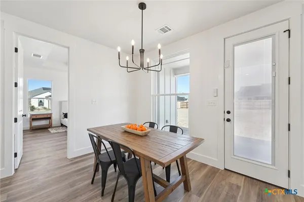 a view of a dining room and livingroom with furniture wooden floor a chandelier