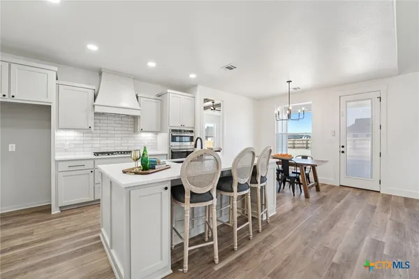 a kitchen with stainless steel appliances kitchen island granite countertop a table chairs and a refrigerator