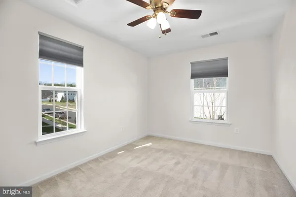 an empty room with windows and fan