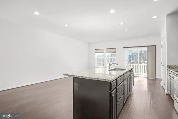 a hallway with granite countertop kitchen island a stove and a wooden floors