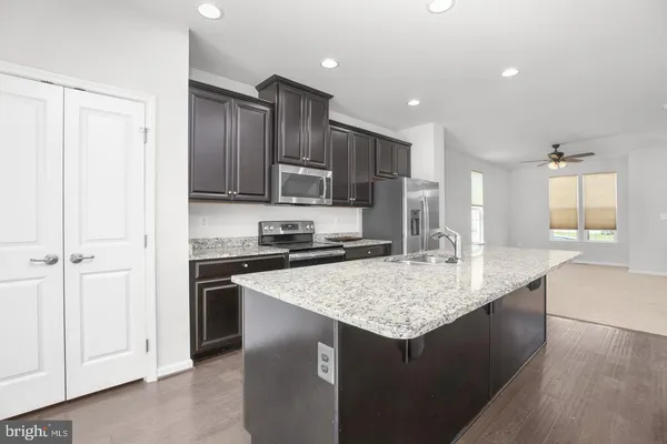 a kitchen with kitchen island granite countertop a sink and a refrigerator