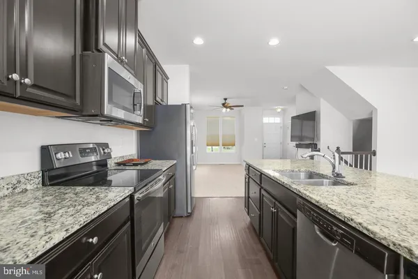 a kitchen with stainless steel appliances granite countertop a sink a stove and a refrigerator