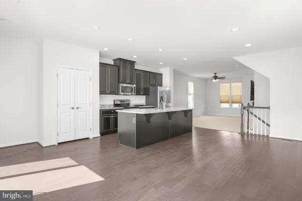 a kitchen with stainless steel appliances kitchen island granite countertop a stove top oven a sink and a refrigerator