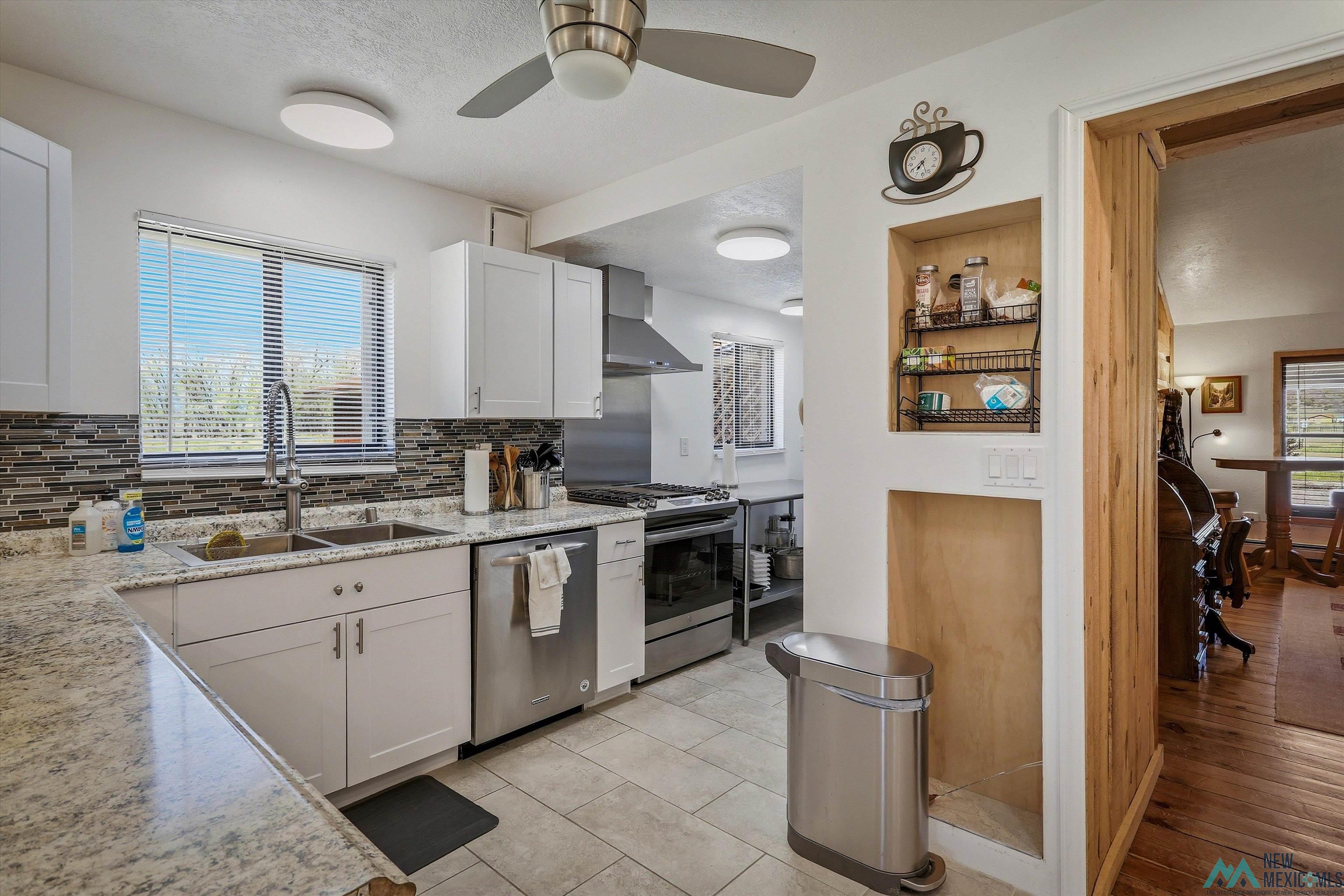 83 Juniper Road Chama, NM 87520 - Photo 9 of 56 Kitchen featuring light-toned cabinetry, stainless steel appliances, speckled countertops, a mosaic tile backsplash, and a double basin sink