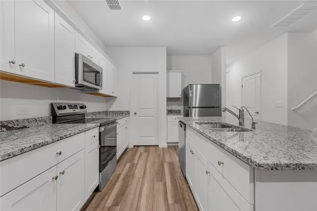 a kitchen with granite countertop stainless steel appliances a sink stove top oven and cabinets