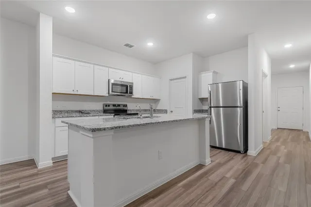 a kitchen with stainless steel appliances granite countertop a refrigerator a stove a sink and a microwave