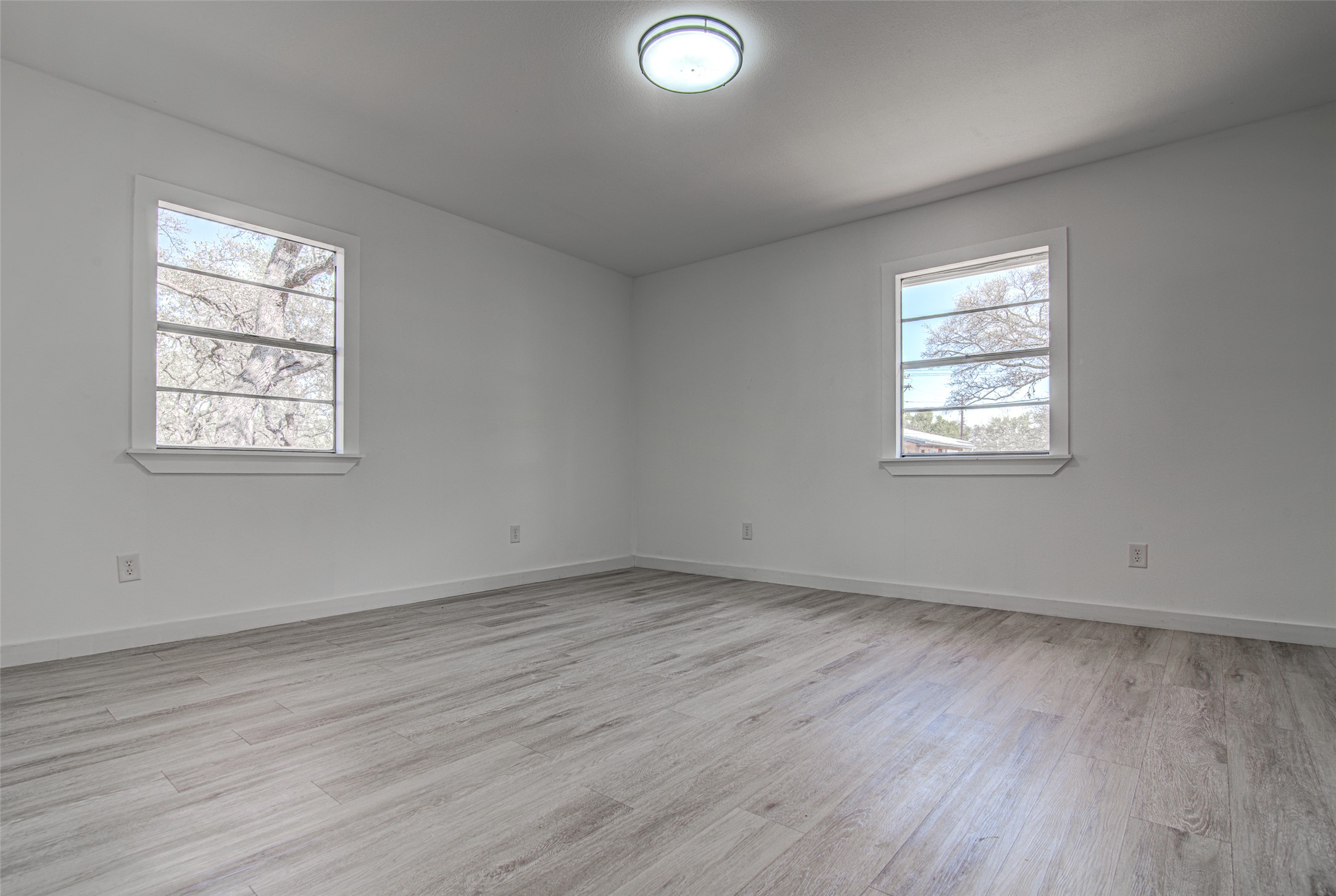 207 Haley Road Johnson City, TX 78636 - Photo 13 of 31 Two windows naturally illuminate this spacious room featuring sleek wood flooring.