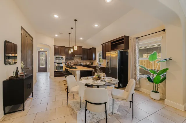 a kitchen with stainless steel appliances kitchen island granite countertop a refrigerator and a dining table