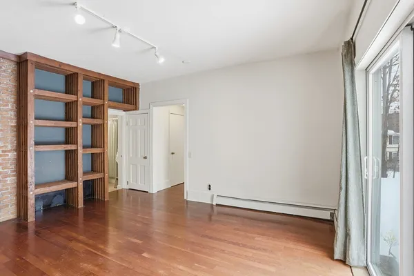 a view of an empty room with a window and wooden floor