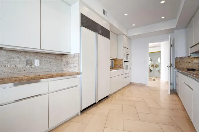 a kitchen with white cabinets and sink