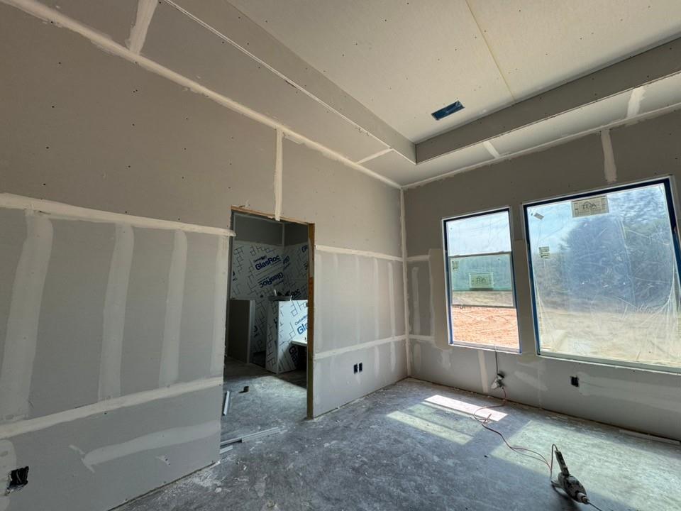 121 Oak Grv Way Springtown, TX 76082 - Photo 9 of 13 Tray ceiling detail, two large windows, drywall installation, and unfinished flooring