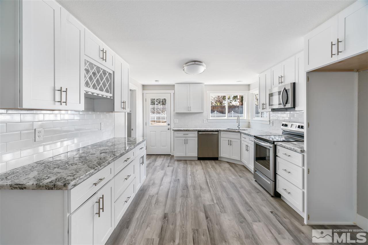 a kitchen with granite countertop a sink cabinets stainless steel appliances and a counter space