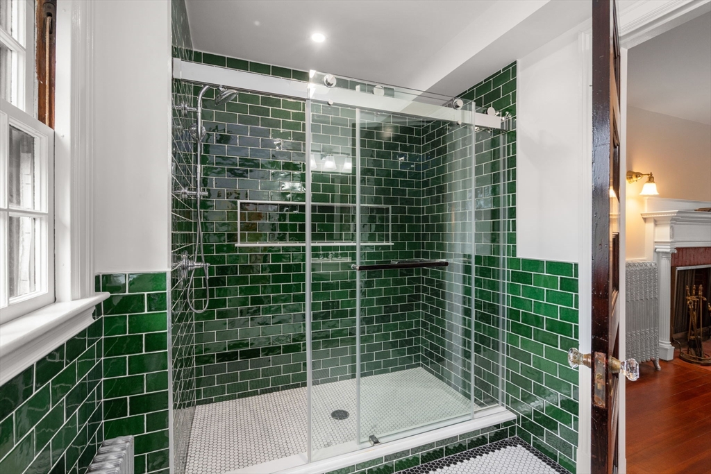 570 Washington Street Dedham, MA 02026 - Photo 28 of 37 a bathroom with a glass shower door and a window