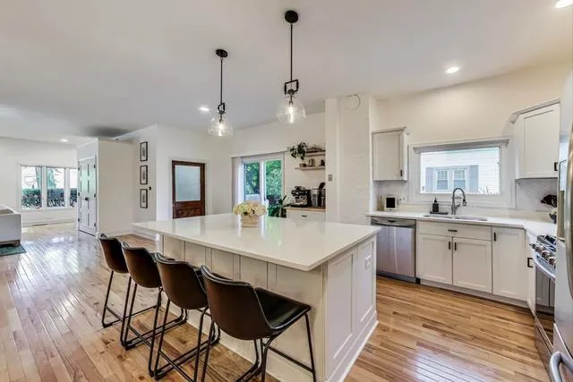 a kitchen with stainless steel appliances kitchen island granite countertop a table chairs in it and white cabinets