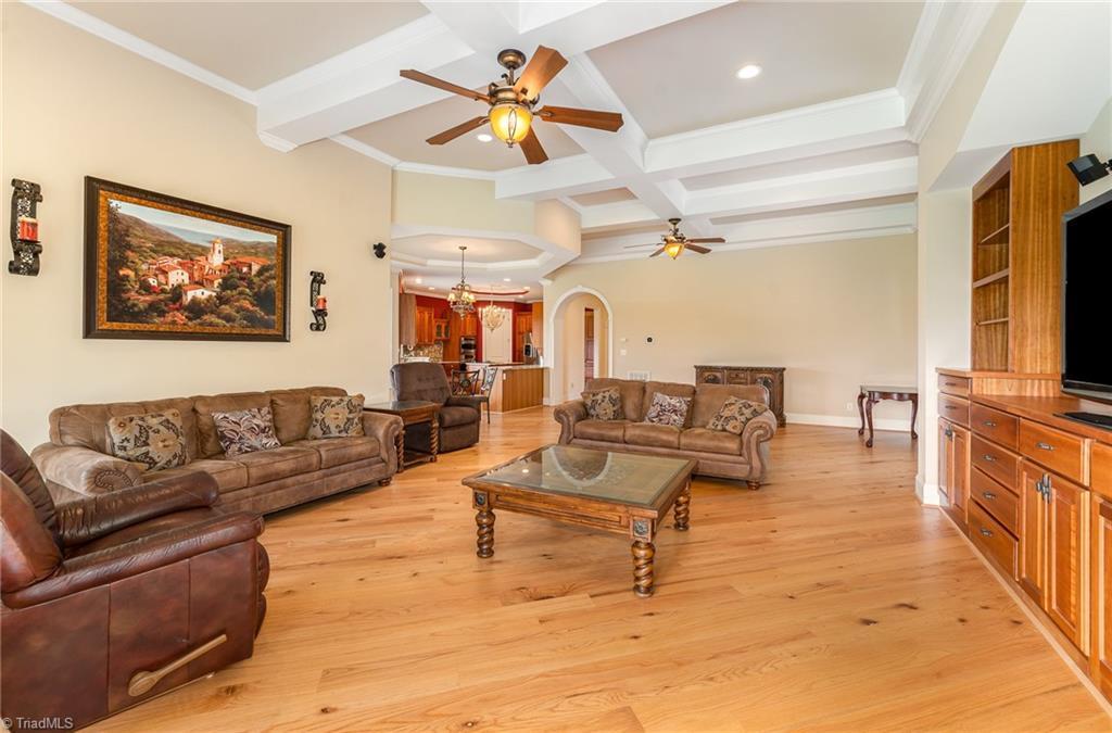 2250 Bethel Church Road Pleasant Garden, NC 27313 - Photo 7 of 45 Inviting family room features custom built-in shelves around the TV, elegant coffered ceilings, and overlooks beautiful hardwood floors, creating a warm and sophisticated space.