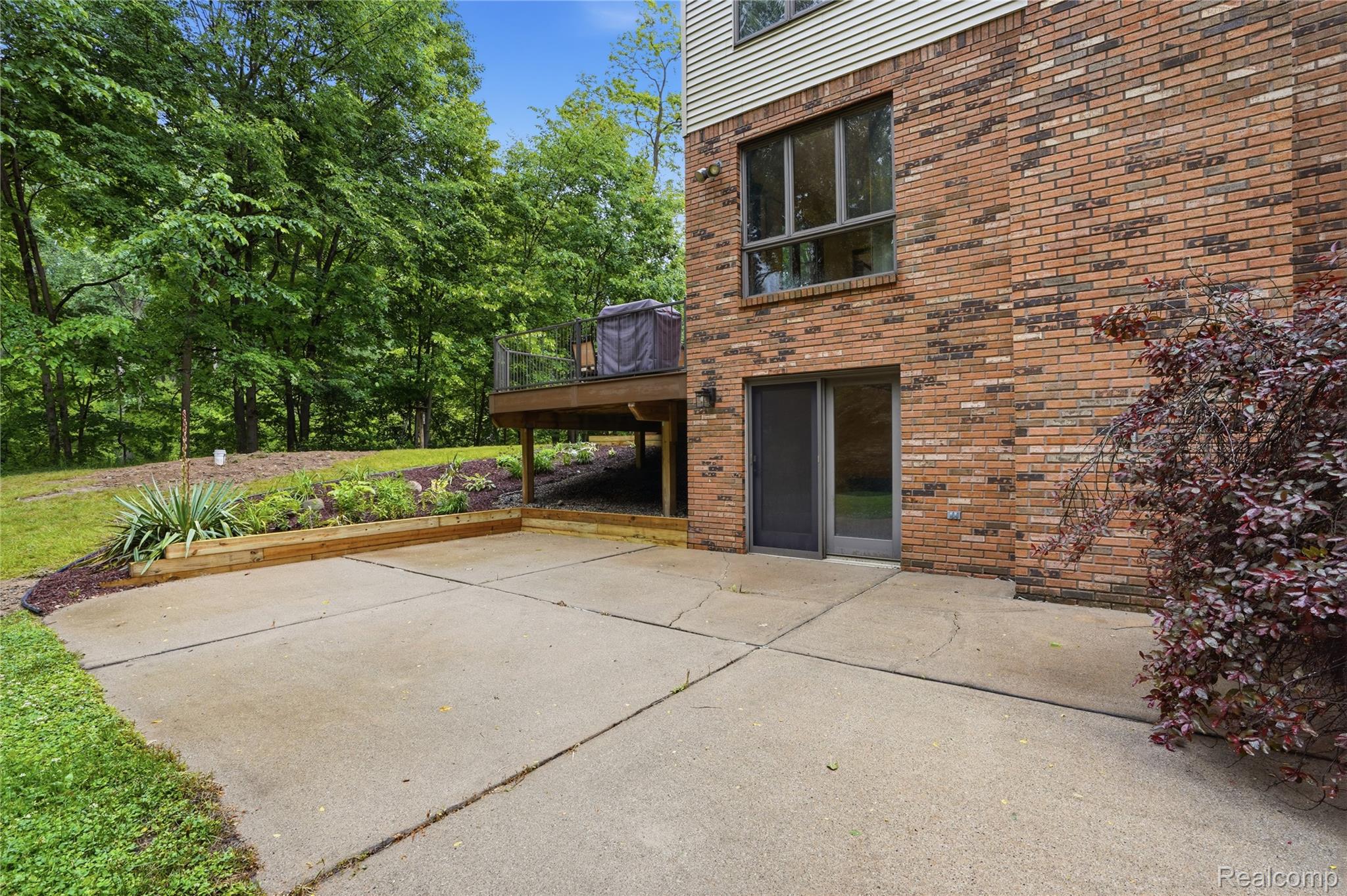 68345 Romeo Plank Road Ray, MI 48096 - Photo 7 of 52 Brick exterior with a large patio, a sliding glass door, and a built-in wooden planter
