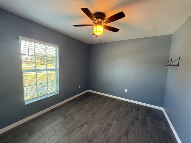 an empty room with ceiling fan and window