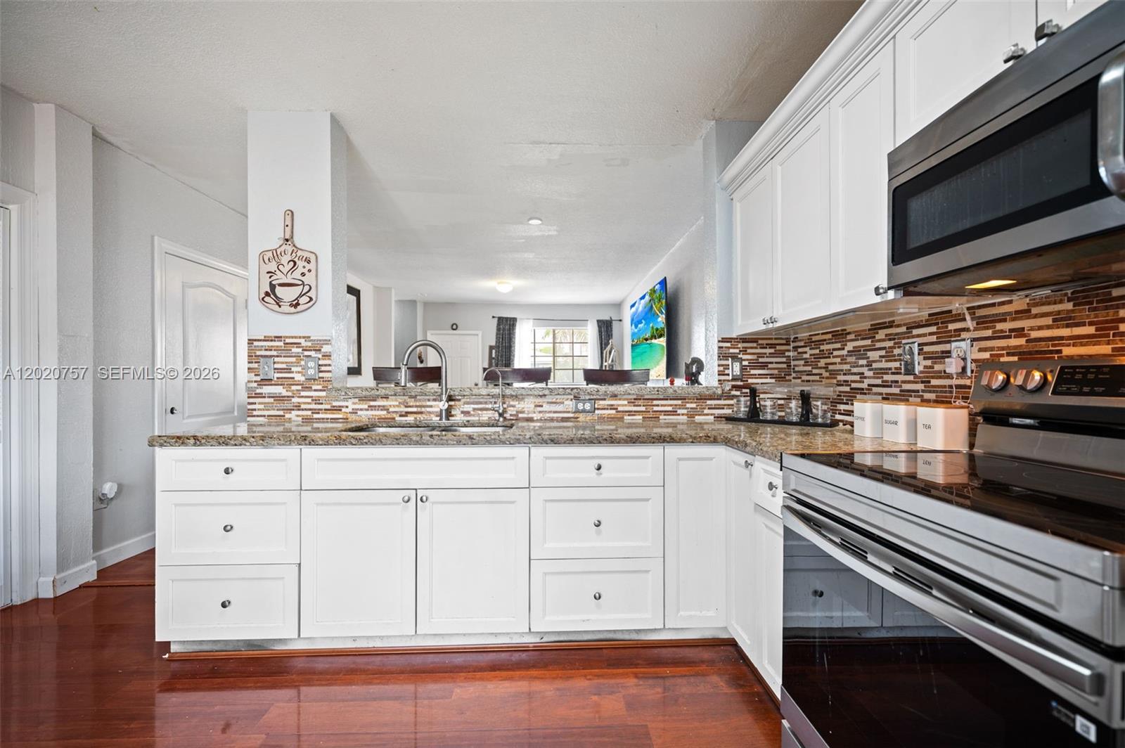 255 East 3rd Street, Unit 1 Hialeah, FL 33010 - Photo 7 of 38 a kitchen with granite countertop white cabinets and stainless steel appliances