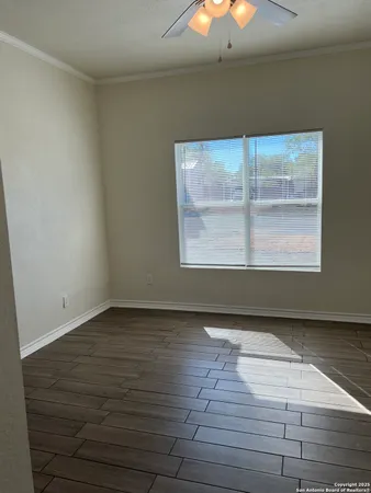 a view of an empty room with wooden floor and a window