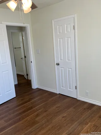 an empty room with wooden floor and chandelier fan