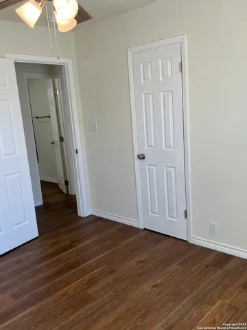 an empty room with wooden floor and chandelier fan