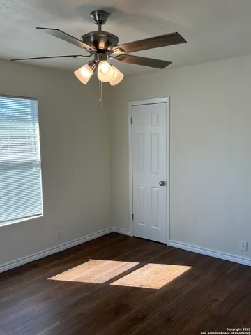 a view of empty room with wooden floor and fan