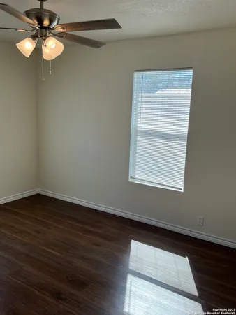 a view of empty room with wooden floor and fan