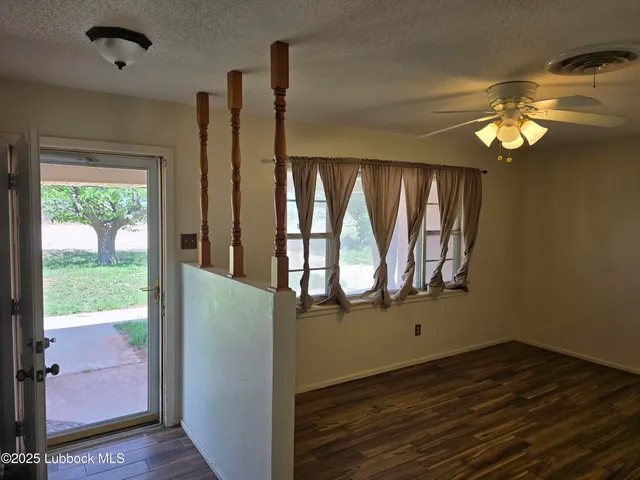 an empty room with wooden floor fan and windows