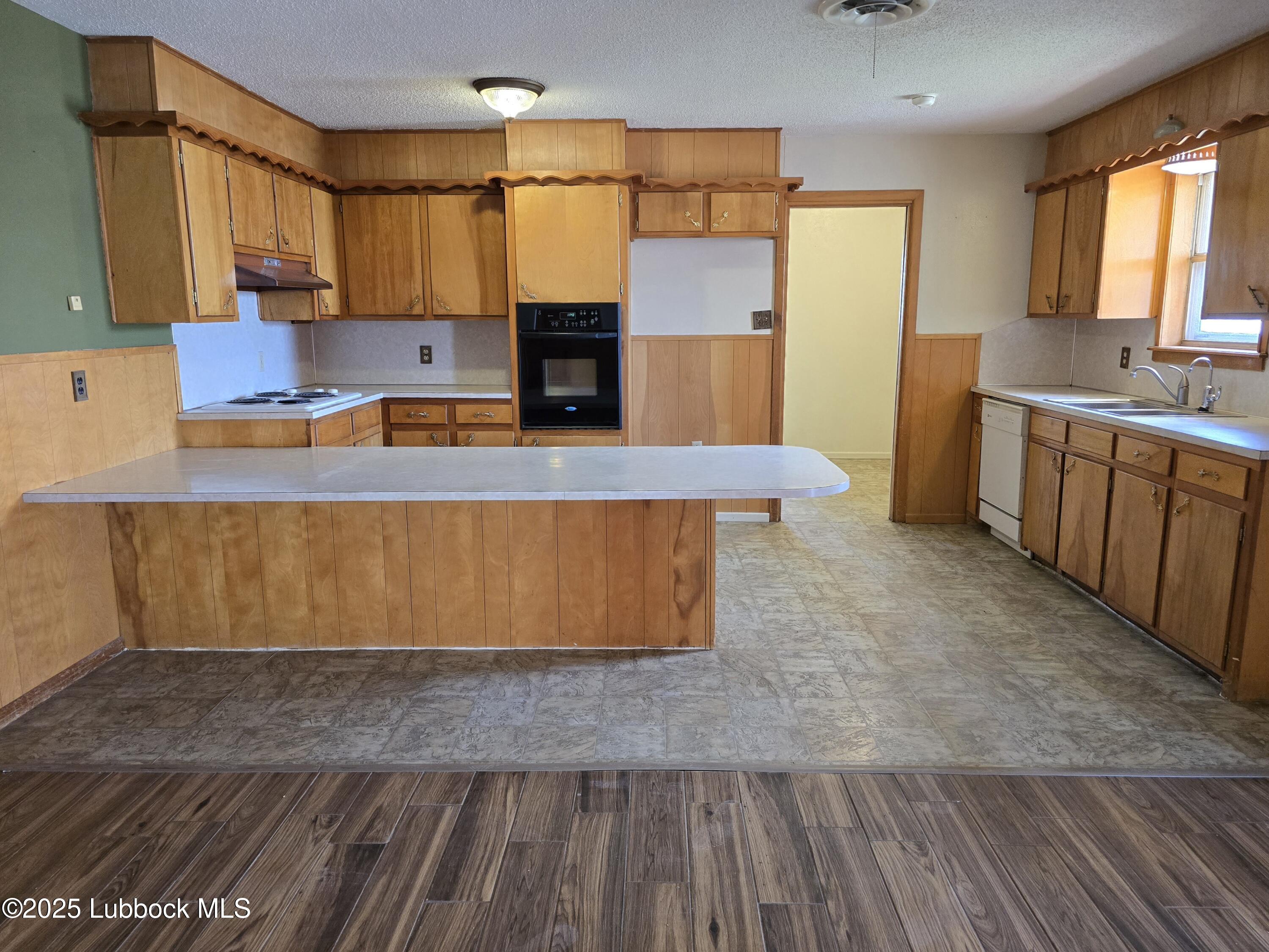 1681 Co Road Denver City, TX 79323 - Photo 9 of 30 a living room with kitchen island granite countertop wooden floor a sink and a stove