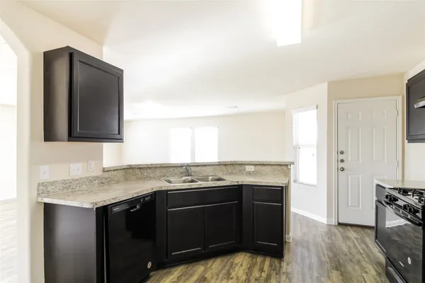 a kitchen with a granite countertop sink stove and cabinets