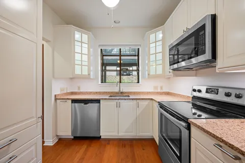 a kitchen with cabinets stainless steel appliances and wooden floor