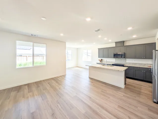 a large kitchen with a large counter top a sink stainless steel appliances and windows