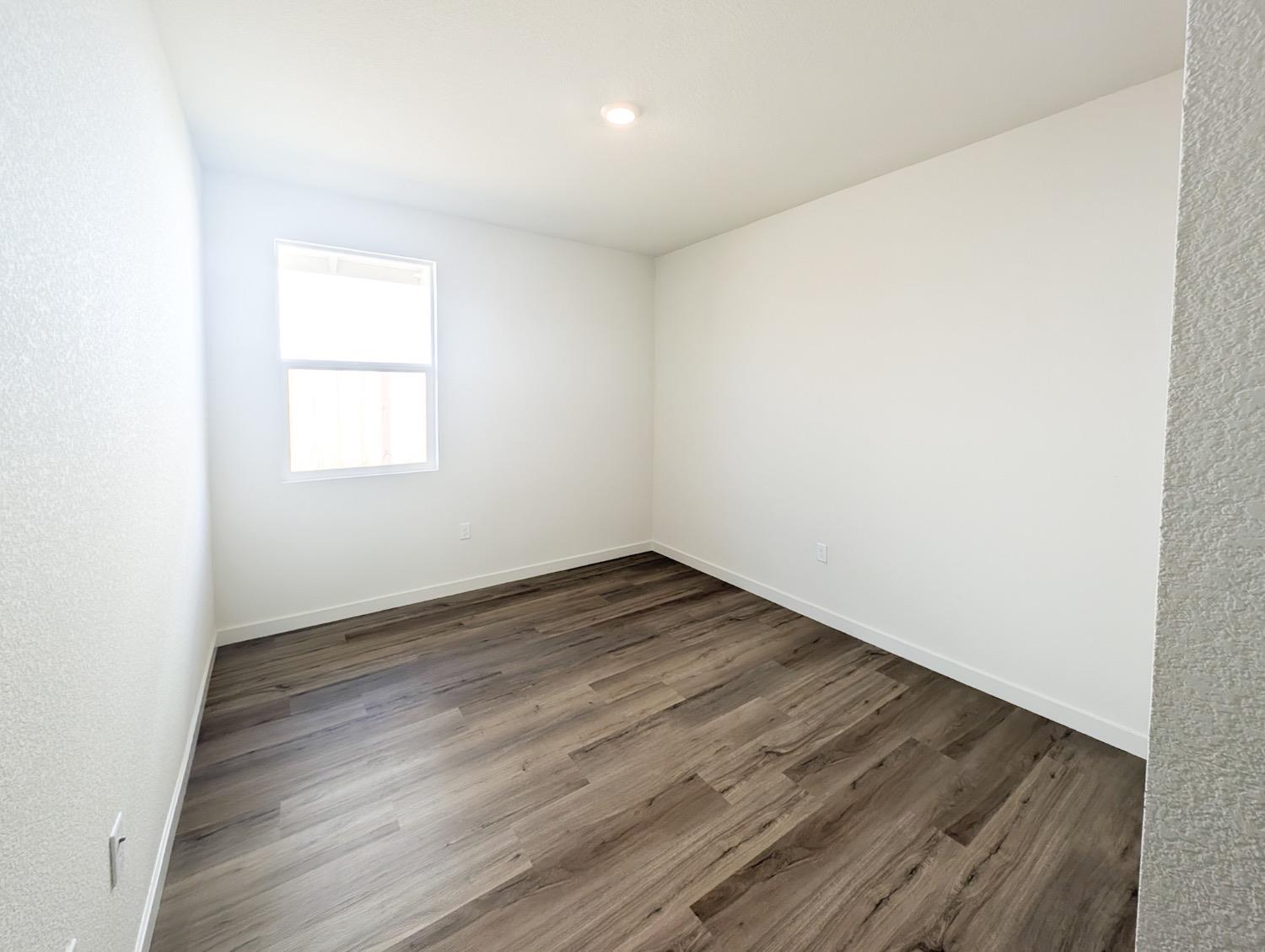 2129 Stagecoach Road Patterson, CA 95363 - Photo 9 of 23 an empty room with wooden floor and windows