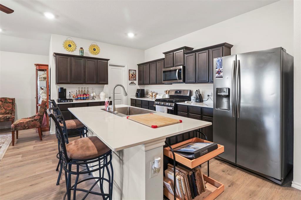 742 Buttercup Drive Pilot Point, TX 76258 - Photo 6 of 20 Kitchen featuring stainless steel appliances, light wood-style flooring, dark brown cabinets, a breakfast bar area, and recessed lighting