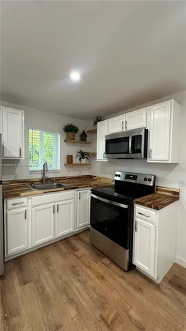 a large kitchen with stainless steel appliances granite countertop a stove a sink dishwasher and a microwave oven with cabinets