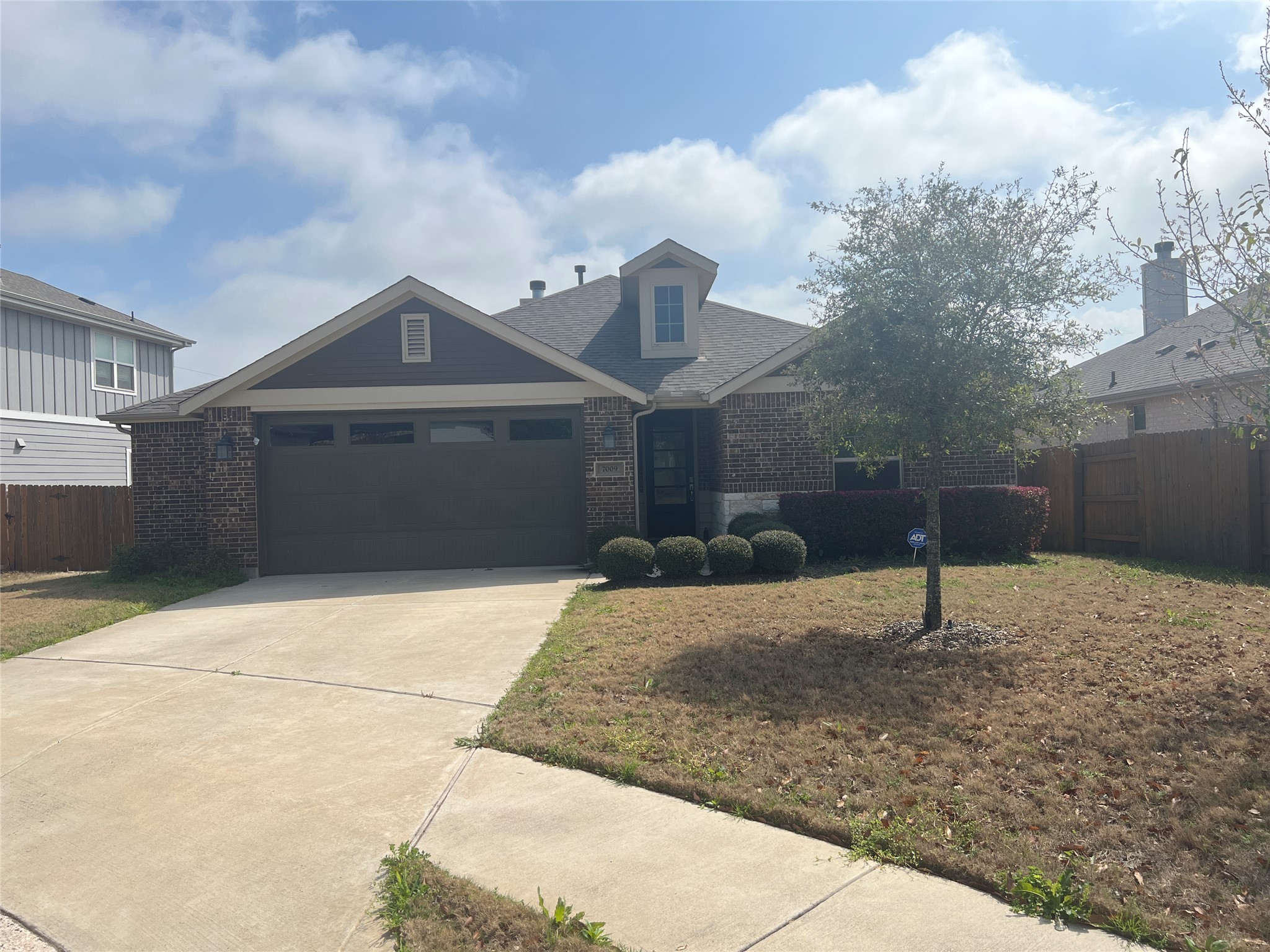 View of front of home featuring brick siding, driveway, and a garage