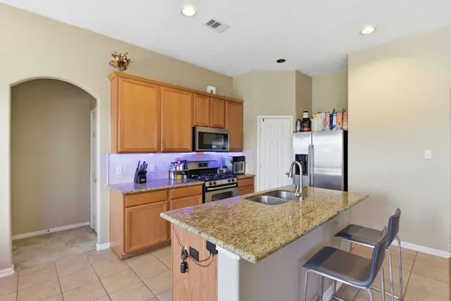 a kitchen with kitchen island granite countertop a sink cabinets and refrigerator