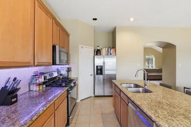 a kitchen with granite countertop a sink stove and refrigerator