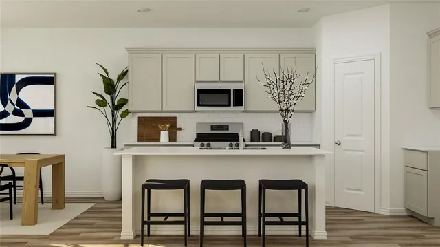 a kitchen with stainless steel appliances a white cabinets and chairs