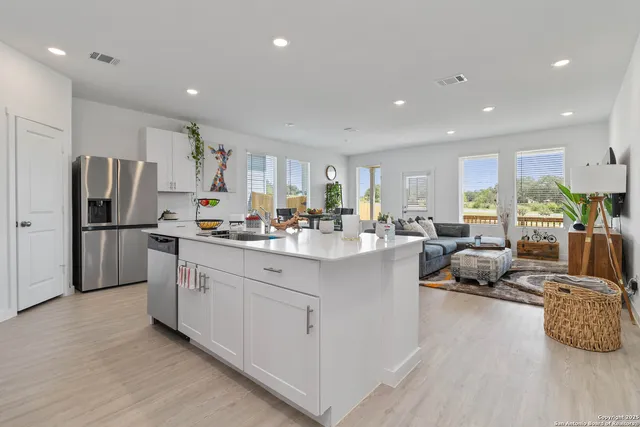 a kitchen with stainless steel appliances granite countertop a refrigerator sink and white cabinets