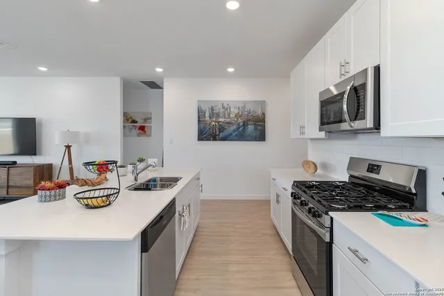 a kitchen with stainless steel appliances a stove a sink a microwave a refrigerator and cabinets