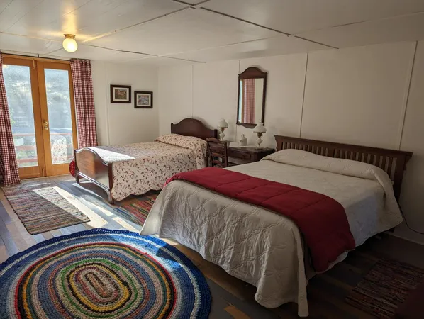 a bedroom with two beds and wooden floor